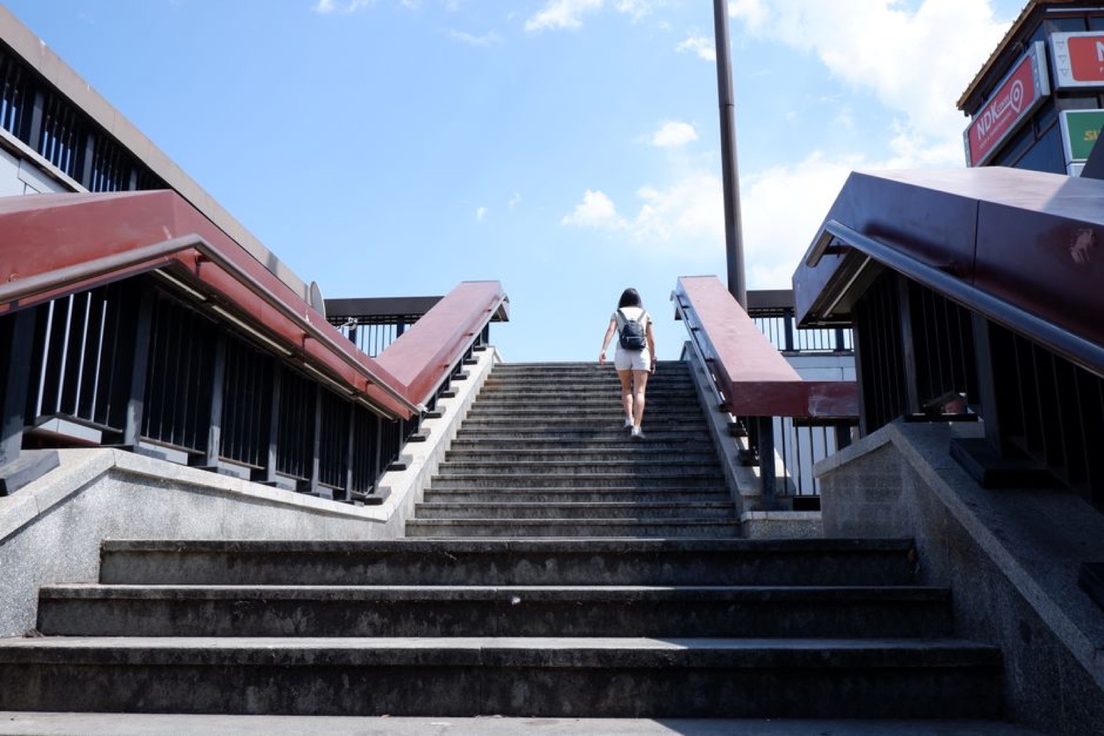 Femme montant un escalier extérieur en ville, symbole du mouvement quotidien